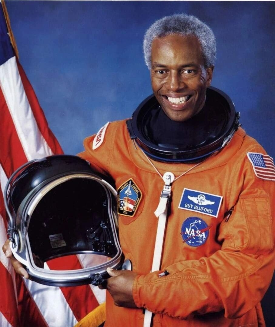 A man in an orange suit holding a helmet.