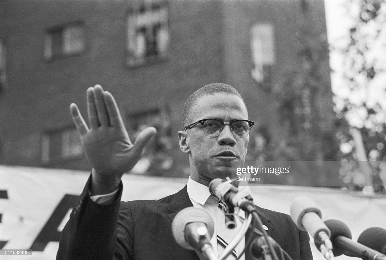 A man in suit and tie holding up his hand.