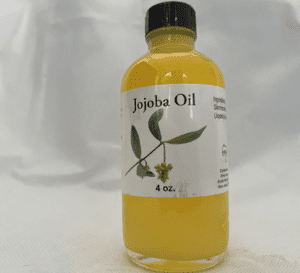 A bottle of jojoba oil sitting on top of a table.