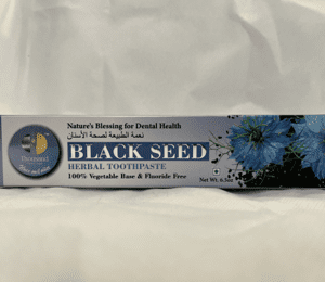 A tube of black seed toothpaste on top of a white sheet.
