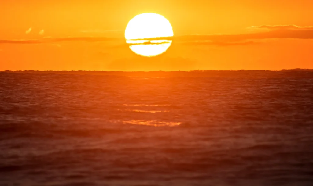 Golden sun setting over calm ocean waves.