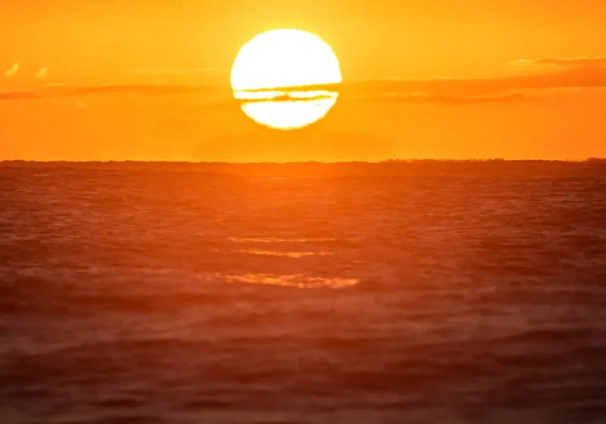 Golden sun setting over calm ocean waves.